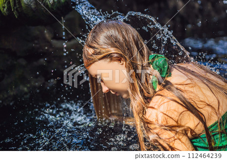 Woman in holy spring water temple in bali. The temple compound consists of a petirtaan or bathing structure, famous for its holy spring water 112464239
