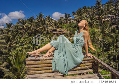 Beautiful young woman walk at typical Asian hillside with rice farming, mountain shape green cascade rice field terraces paddies. Ubud, Bali, Indonesia. Bali travel concept Beautiful young woman walk at typical Asian hillside with rice farming, mountain shape green cascade rice field terraces paddies. Ubud, Bali, Indonesia. Bali travel concept 112464684