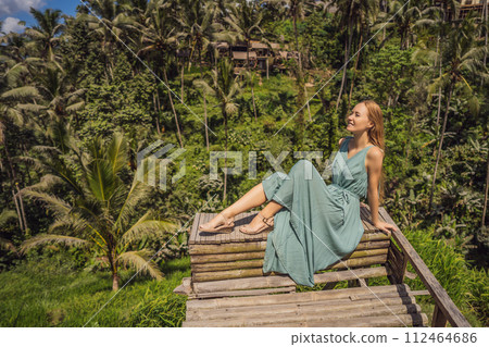 Beautiful young woman walk at typical Asian hillside with rice farming, mountain shape green cascade rice field terraces paddies. Ubud, Bali, Indonesia. Bali travel concept Beautiful young woman walk at typical Asian hillside with rice farming, mountain shape green cascade rice field terraces paddies. Ubud, Bali, Indonesia. Bali travel concept 112464686