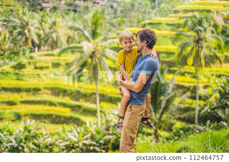 Dad and son travelers on Beautiful Rice Terraces against the background of famous volcanoes in Bali, Indonesia Traveling with children concept Dad and son travelers on Beautiful Rice Terraces against the background of famous volcanoes in Bali, Indonesia Traveling with children concept 112464757