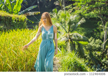Beautiful young woman walk at typical Asian hillside with rice farming, mountain shape green cascade rice field terraces paddies. Ubud, Bali, Indonesia. Bali travel concept 112464806
