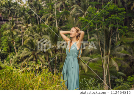 Beautiful young woman walk at typical Asian hillside with rice farming, mountain shape green cascade rice field terraces paddies. Ubud, Bali, Indonesia. Bali travel concept 112464815