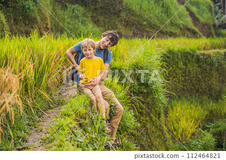 Dad and son travelers on Beautiful Rice Terraces against the background of famous volcanoes in Bali, Indonesia Traveling with children concept Dad and son travelers on Beautiful Rice Terraces against the background of famous volcanoes in Bali, Indonesia Traveling with children concept 112464821