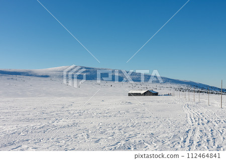 Winter morning, road to Meadow Hut, krkonose mountains. Along the road are wooden long bars, tourist markings for winter season. 112464841