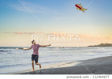 young men flying a kite at sunset on the beach young men flying a kite at sunset on the beach 112464877