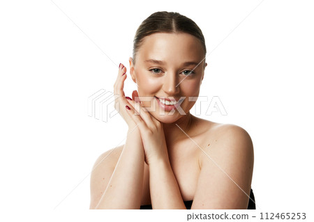 Young woman with contented smile showing natural look that epitomizes simplicity against white studio background. 112465253