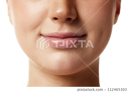 Close up photo of young woman with beautiful, plump, moisturized lips against white studio background. Lips with natural gloss. 112465303