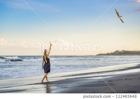 A young woman launches a kite on the beach. Dream, aspirations, future plans A young woman launches a kite on the beach. Dream, aspirations, future plans 112465648