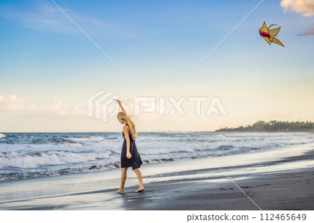 A young woman launches a kite on the beach. Dream, aspirations, future plans A young woman launches a kite on the beach. Dream, aspirations, future plans 112465649