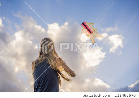 A young woman launches a kite on the beach. Dream, aspirations, future plans A young woman launches a kite on the beach. Dream, aspirations, future plans 112465676