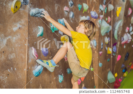 little boy climbing a rock wall in special boots. indoor little boy climbing a rock wall in special boots. indoor 112465748