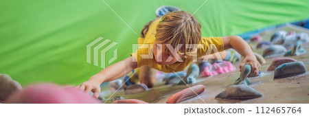 little boy climbing a rock wall in special boots. indoor BANNER, LONG FORMAT 112465764