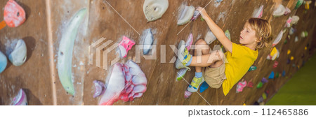 little boy climbing a rock wall in special boots. indoor BANNER, LONG FORMAT 112465886