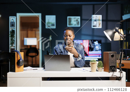 Female freelancer embraces the digital age as she looks for products online, leveraging her personal computer. Young black woman grasping debit card spending money on e commerce platforms. Female freelancer embraces the digital age as she looks for products online, leveraging her personal computer. Young black woman grasping debit card spending money on e commerce platforms. 112466128