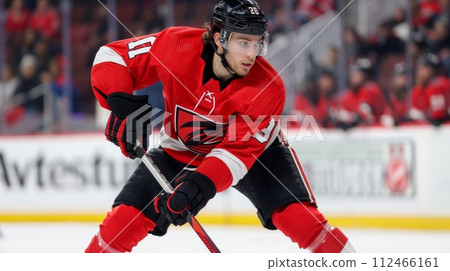 AI-generated content. Portrait of young man, hockey player with concentrated and serious gaze, in red uniform and protective helmet on blurred tribune background 112466161