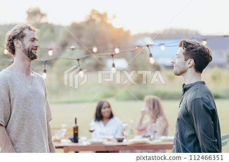 Evening Revelries: Friends Sharing Laughter at a Garden Party 112466351