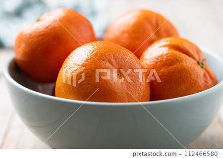 Fresh tangerines in bowl on wooden table 112466580