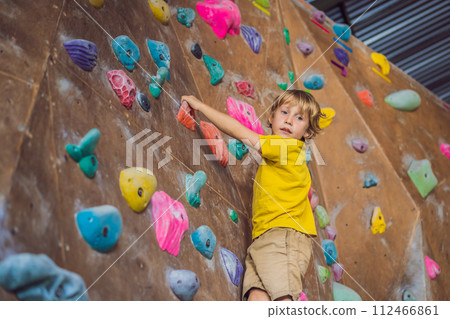 little boy climbing a rock wall in special boots. indoor 112466861
