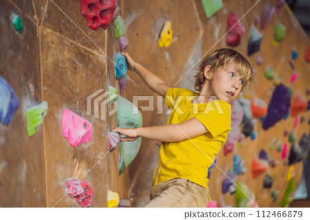 little boy climbing a rock wall in special boots. indoor 112466879