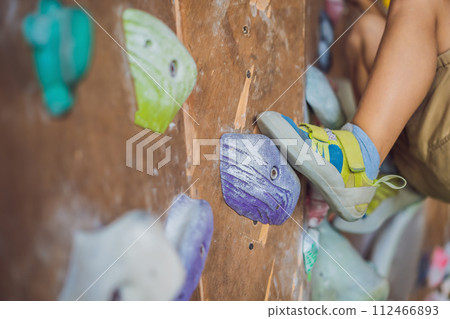 little boy climbing a rock wall in special boots. indoor little boy climbing a rock wall in special boots. indoor 112466893