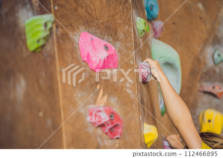 little boy climbing a rock wall in special boots. indoor little boy climbing a rock wall in special boots. indoor 112466895