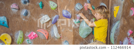 little boy climbing a rock wall in special boots. indoor BANNER, LONG FORMAT 112466914