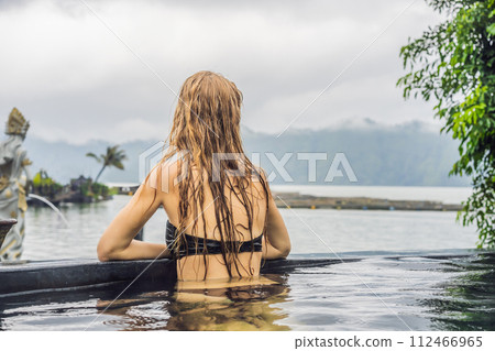 Geothermal spa. Woman relaxing in hot spring pool against the lake. hot springs concept 112466965