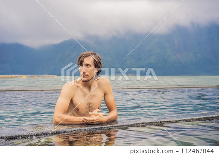 Geothermal spa. Man relaxing in hot spring pool. Young man enjoying bathing relaxed in a blue water lagoon, tourist attraction Geothermal spa. Man relaxing in hot spring pool. Young man enjoying bathing relaxed in a blue water lagoon, tourist attraction 112467044