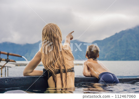 Mom and son travelers in Hot Springs in Bali on the background of lake. Traveling with children concept 112467060