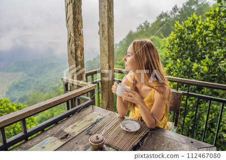 Young woman drinks coffee in a cafe in the mountains 112467080