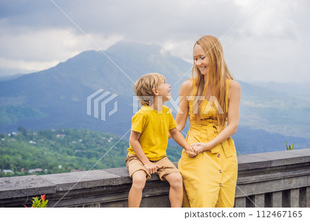 Mom and son tourists on background looking at Batur volcano. Indonesia. Traveling with kids concept Mom and son tourists on background looking at Batur volcano. Indonesia. Traveling with kids concept 112467165