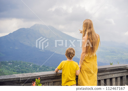 Mom and son tourists on background looking at Batur volcano. Indonesia. Traveling with kids concept Mom and son tourists on background looking at Batur volcano. Indonesia. Traveling with kids concept 112467167