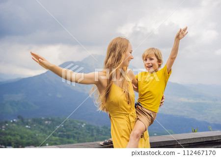 Mom and son tourists on background looking at Batur volcano. Indonesia. Traveling with kids concept Mom and son tourists on background looking at Batur volcano. Indonesia. Traveling with kids concept 112467170