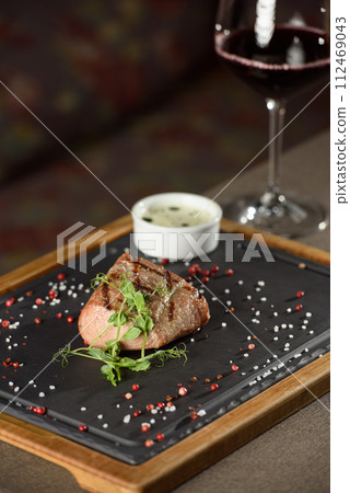 Succulent grilled beef steak with red wine, seasonings, fresh rosemary and grilled vegetables on cutting board Succulent grilled beef steak with red wine, seasonings, fresh rosemary and grilled vegetables on cutting board 112469043