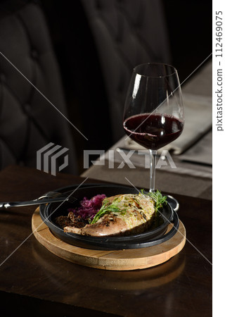 Chicken leg stuffed, served with vegetables on a black plate Chicken leg stuffed, served with vegetables on a black plate 112469075