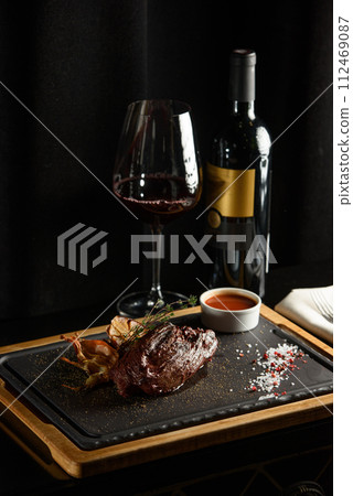 Succulent grilled beef steak with red wine, seasonings, fresh rosemary and grilled vegetables on cutting board Succulent grilled beef steak with red wine, seasonings, fresh rosemary and grilled vegetables on cutting board 112469087