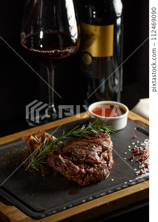 Succulent grilled beef steak with red wine, seasonings, fresh rosemary and grilled vegetables on cutting board Succulent grilled beef steak with red wine, seasonings, fresh rosemary and grilled vegetables on cutting board 112469090