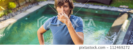 BANNER, LONG FORMAT Young man with disgust on his face pinches nose, something stinks, very bad smell in swimming pool because of pool chemicals. Negative emotion facial expression 112469272