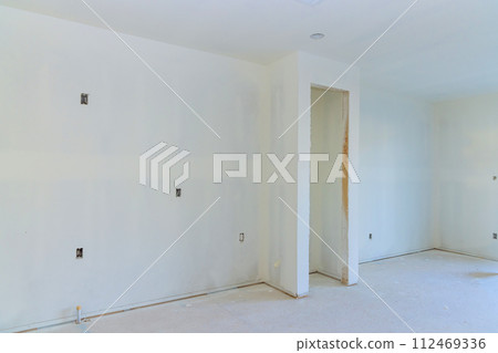 Having completed painting decorating work on new house, preparing walls for final painting 112469336