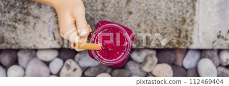Young woman drinking Dragon fruit smoothies on the background of the pool. Fruit smoothie - healthy eating concept. Close up of detox smoothie with Dragon fruit BANNER, LONG FORMAT 112469404