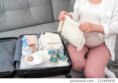 Woman in late pregnancy packing things for maternity hospital Woman in late pregnancy packing things for maternity hospital 112469456