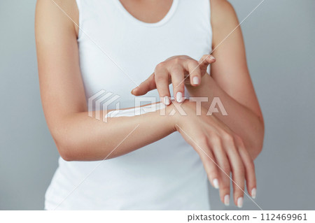 Closeup shot of woman hands holding cream and applying moisturizing hand cream. Beautiful female hands with cream. Hand Skin Care. A woman uses body lotion on your arms. Beauty And Body Care Concept 112469961