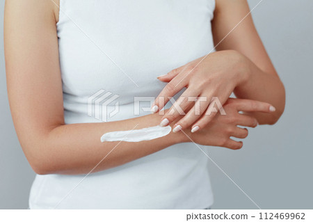 Closeup shot of woman hands holding cream and applying moisturizing hand cream. Beautiful female hands with cream. Hand Skin Care. A woman uses body lotion on your arms. Beauty And Body Care Concept 112469962