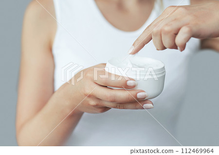 Closeup shot of woman hands holding cream and applying moisturizing hand cream. Beautiful female hands with cream. Hand Skin Care. A woman uses body lotion on your arms. Beauty And Body Care Concept Closeup shot of woman hands holding cream and applying moisturizing hand cream. Beautiful female hands with cream. Hand Skin Care. A woman uses body lotion on your arms. Beauty And Body Care Concept 112469964