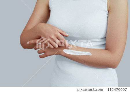 Closeup shot of woman hands holding cream and applying moisturizing hand cream. Beautiful female hands with cream. Hand Skin Care. A woman uses body lotion on your arms. Beauty And Body Care Concept Closeup shot of woman hands holding cream and applying moisturizing hand cream. Beautiful female hands with cream. Hand Skin Care. A woman uses body lotion on your arms. Beauty And Body Care Concept 112470007