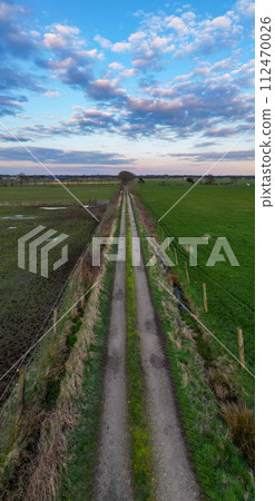 Country Road Embraced by Twilight Sky: Aerial Journey Through Farmland 112470026