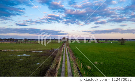 Twilight Descends on a Rural Pathway Framed by Pastoral Fields and Sky Twilight Descends on a Rural Pathway Framed by Pastoral Fields and Sky 112470032