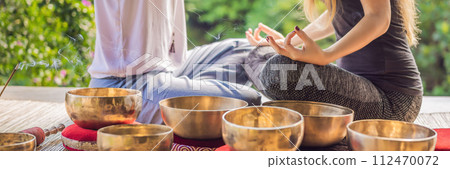 BANNER, LONG FORMAT Nepal Buddha copper singing bowl at spa salon. Young beautiful woman doing massage therapy singing bowls in the Spa against a waterfall. Sound therapy, recreation, meditation BANNER, LONG FORMAT Nepal Buddha copper singing bowl at spa salon. Young beautiful woman doing massage therapy singing bowls in the Spa against a waterfall. Sound therapy, recreation, meditation 112470072