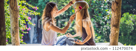 BANNER, LONG FORMAT Nepal Buddha copper singing bowl at spa salon. Young beautiful woman doing massage therapy singing bowls in the Spa against a waterfall. Sound therapy, recreation, meditation 112470074