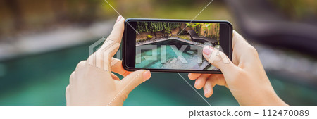 hand holding phone on background of the pool in hotel. photo camera on the screen. close up hand hold smartphone take a picture of summer vacation BANNER, LONG FORMAT 112470089